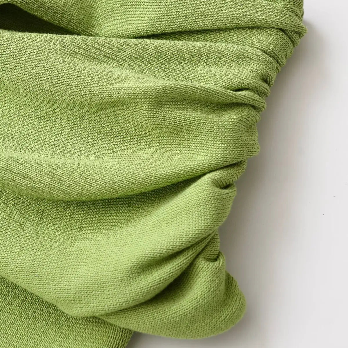 Close-up of the ruched bust on green knit halter dress, showing soft fabric texture and stitching.