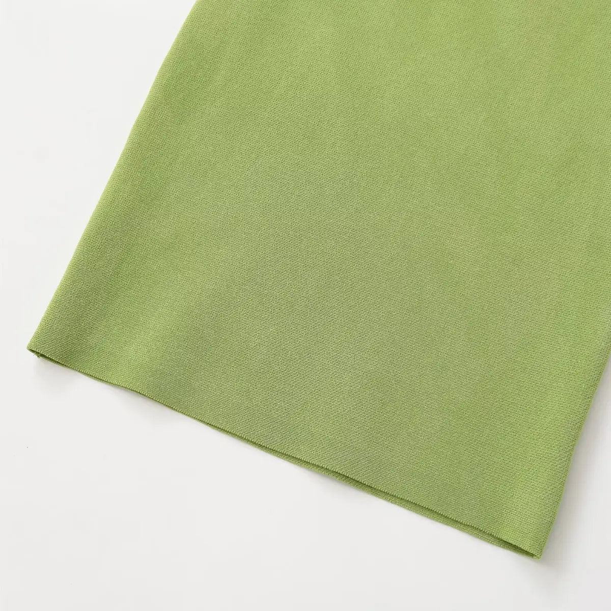 Close-up of the skirt hem on green knit halter dress, showing smooth knit fabric and neat finish.