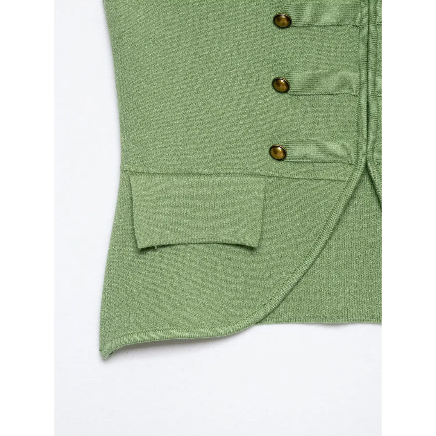 Close‑up of front patch pocket and curved hem edge on sage green tailored knit vest