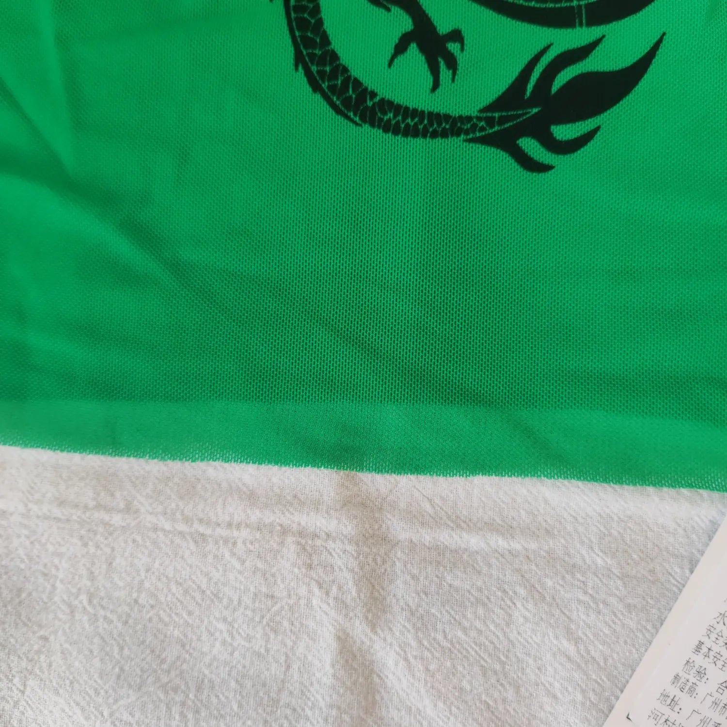 Close‑up bottom hem finished seam and sheer mesh fabric texture green graphic cropped tank top