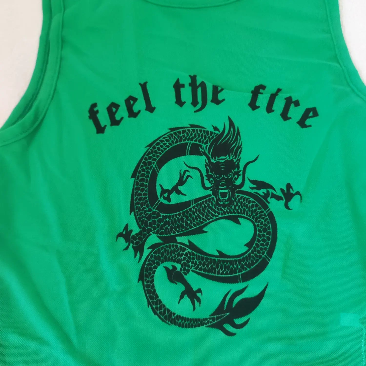Extreme close‑up front dragon illustration and feel the fire text print on green mesh crop tank top