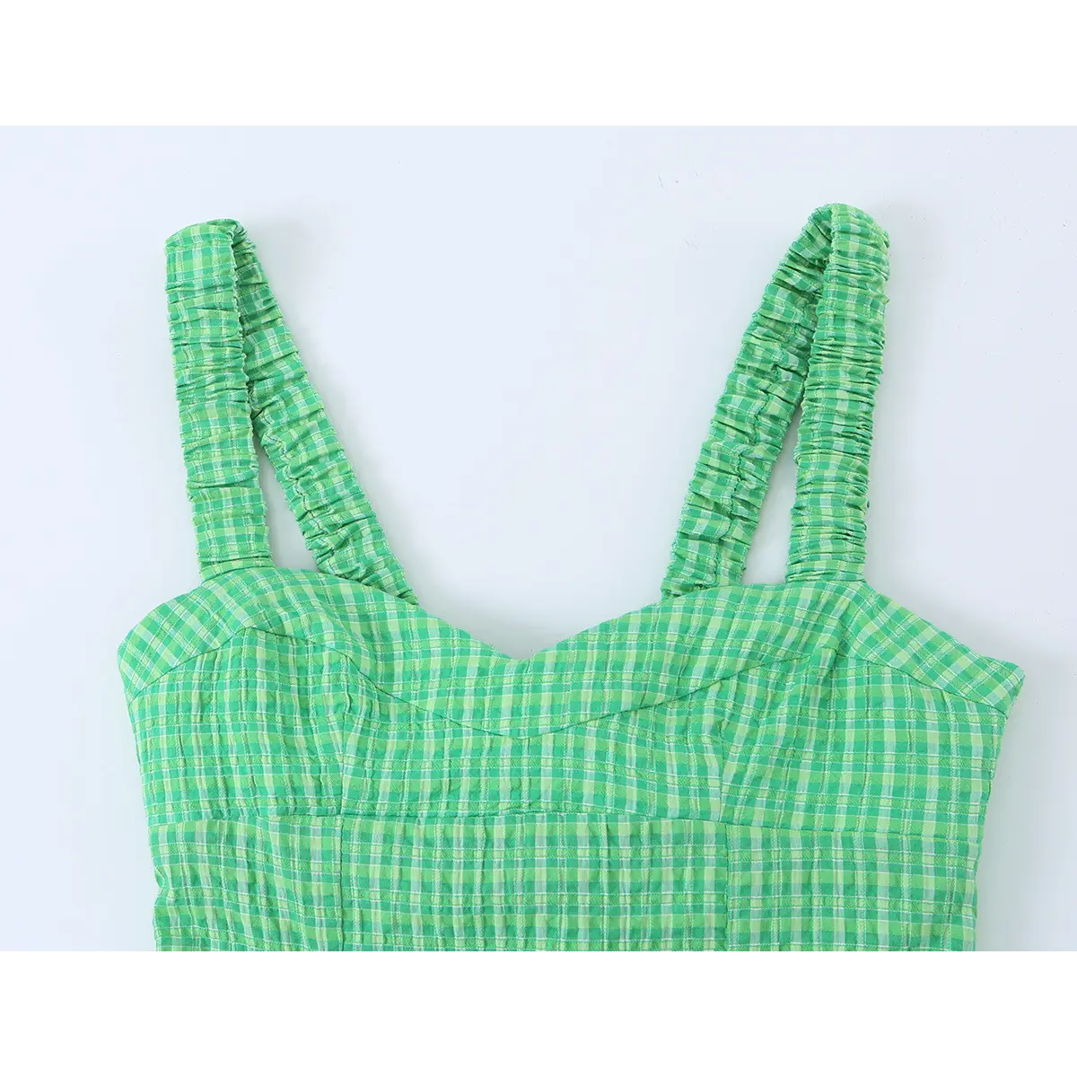 Close-up of the dress's sweetheart neckline and smocked straps, showing the green gingham fabric and stitching.