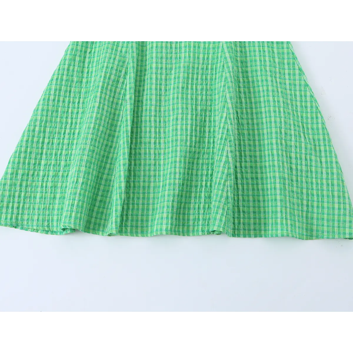 Close-up of the dress's flared skirt hem, displaying the gingham pattern and soft, textured fabric.