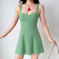 The green gingham dress styled on a model, highlighting its form-fitting bodice, A-line silhouette, and how it pairs with accessories.