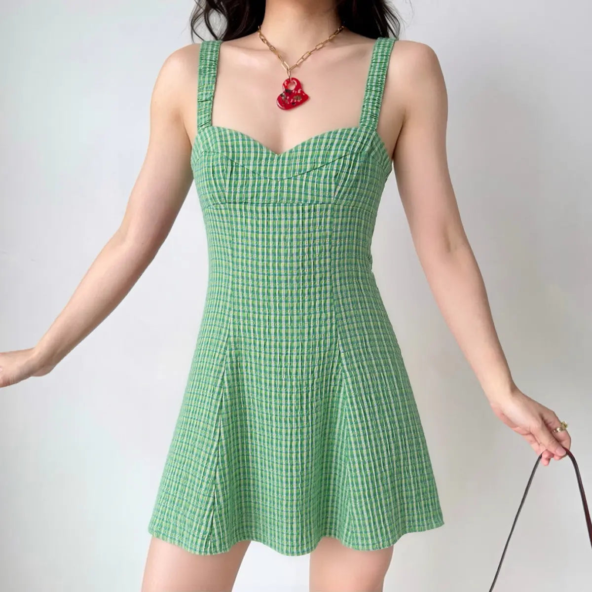 The green gingham dress styled on a model, highlighting its form-fitting bodice, A-line silhouette, and how it pairs with accessories.