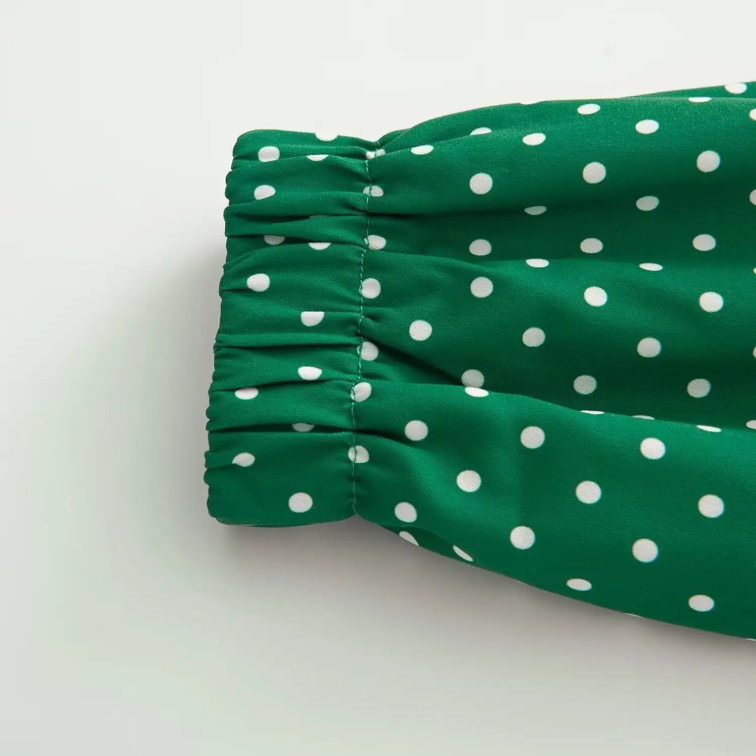 Elastic cuff detail of green jacket with evenly distributed white polka dots