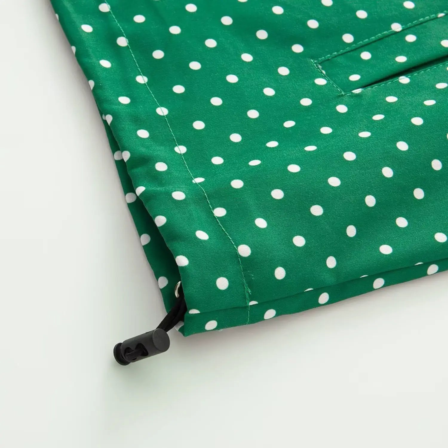 Bottom hem drawstring toggle detail of green polka dot windbreaker