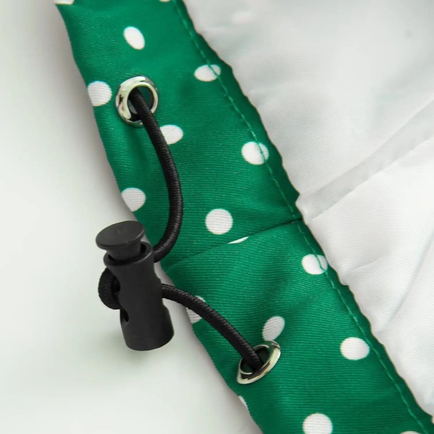 Inner drawstring and metal eyelet close-up on green polka dot jacket