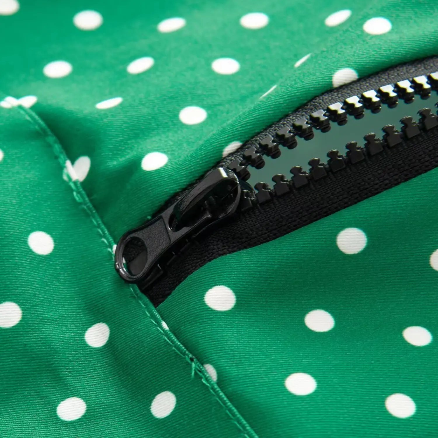 Close-up shot of black half zipper on green white polka dot pullover jacket