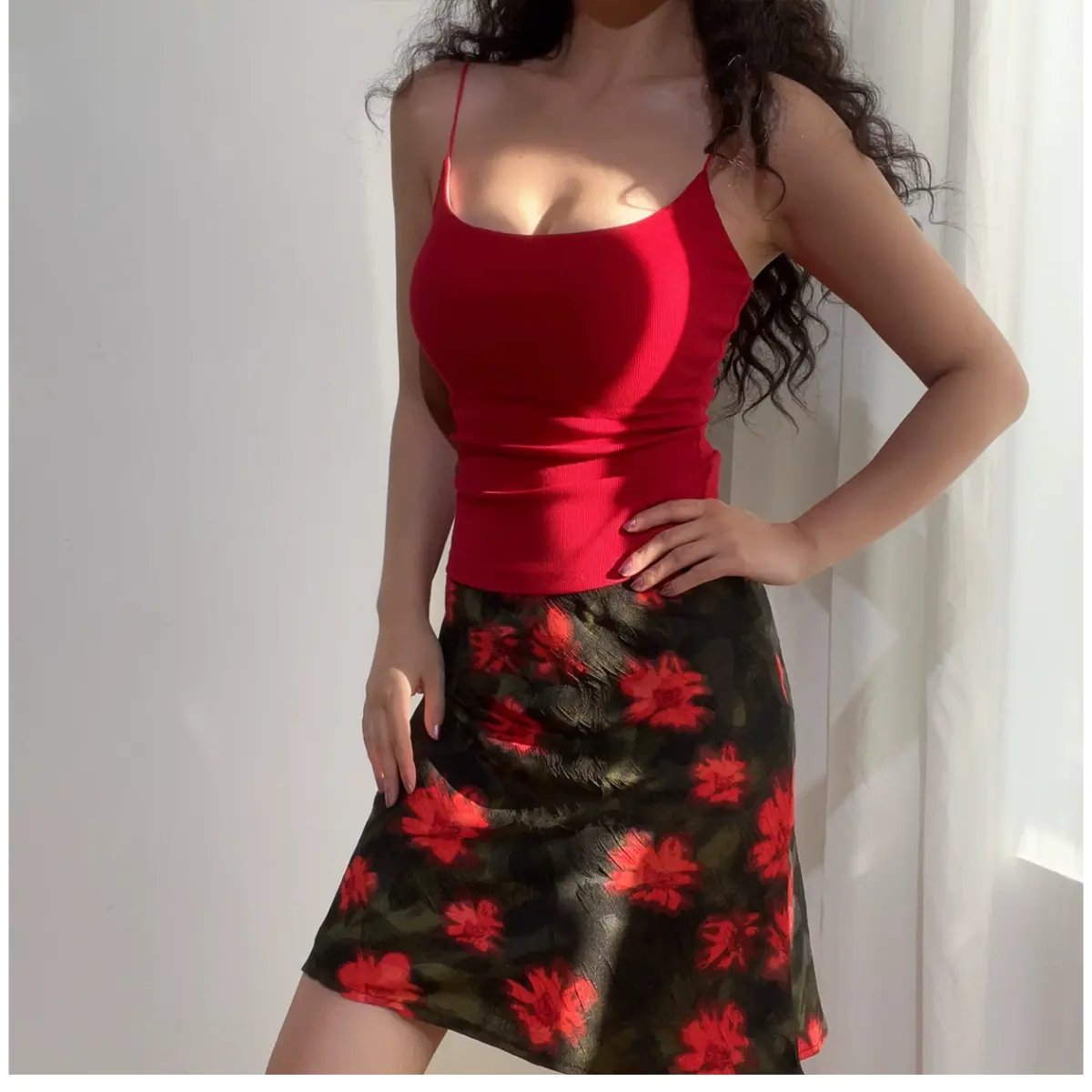 Full front view of a woman wearing a green and red floral chiffon mini skirt, paired with a red ribbed camisole, showing the complete outfit.