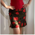 Close-up view of a green and red floral chiffon mini skirt, paired with a red ribbed camisole, showing the print and fabric texture.