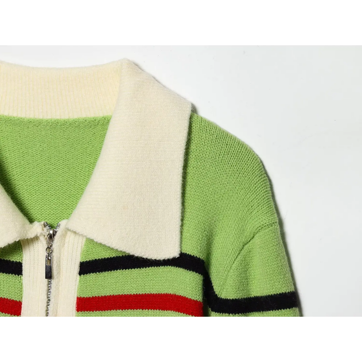 Close-up of cream collar and metal half zip on green knit sweater with striped shoulder