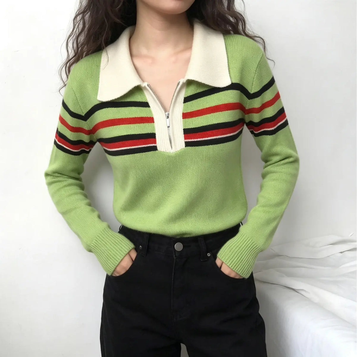 Model wearing green stripe trim knit sweater with black jeans on white background