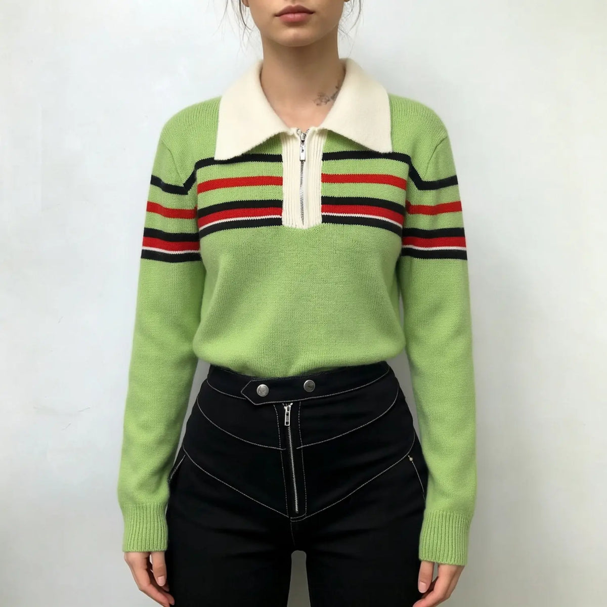 Model wearing avocado green knit sweater with collar zip and stripe trim with black trousers
