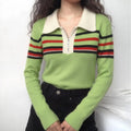 Model wearing green knit sweater with cream collar and black red white stripes, paired with black jeans