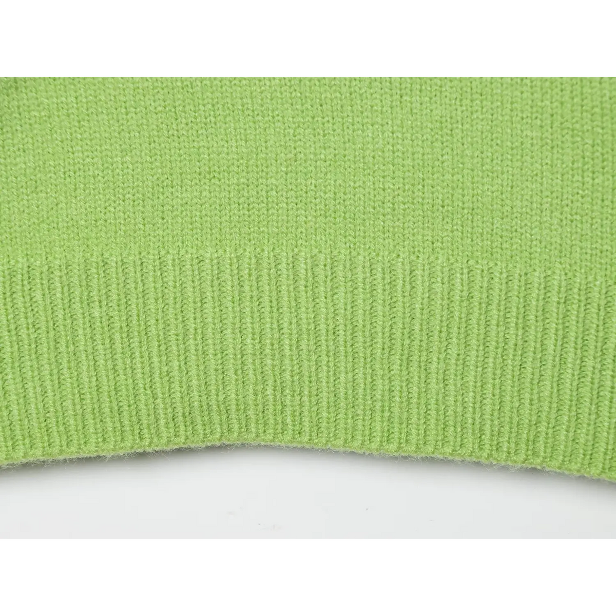 Close-up of fine knit fabric with ribbed trim on green sweater