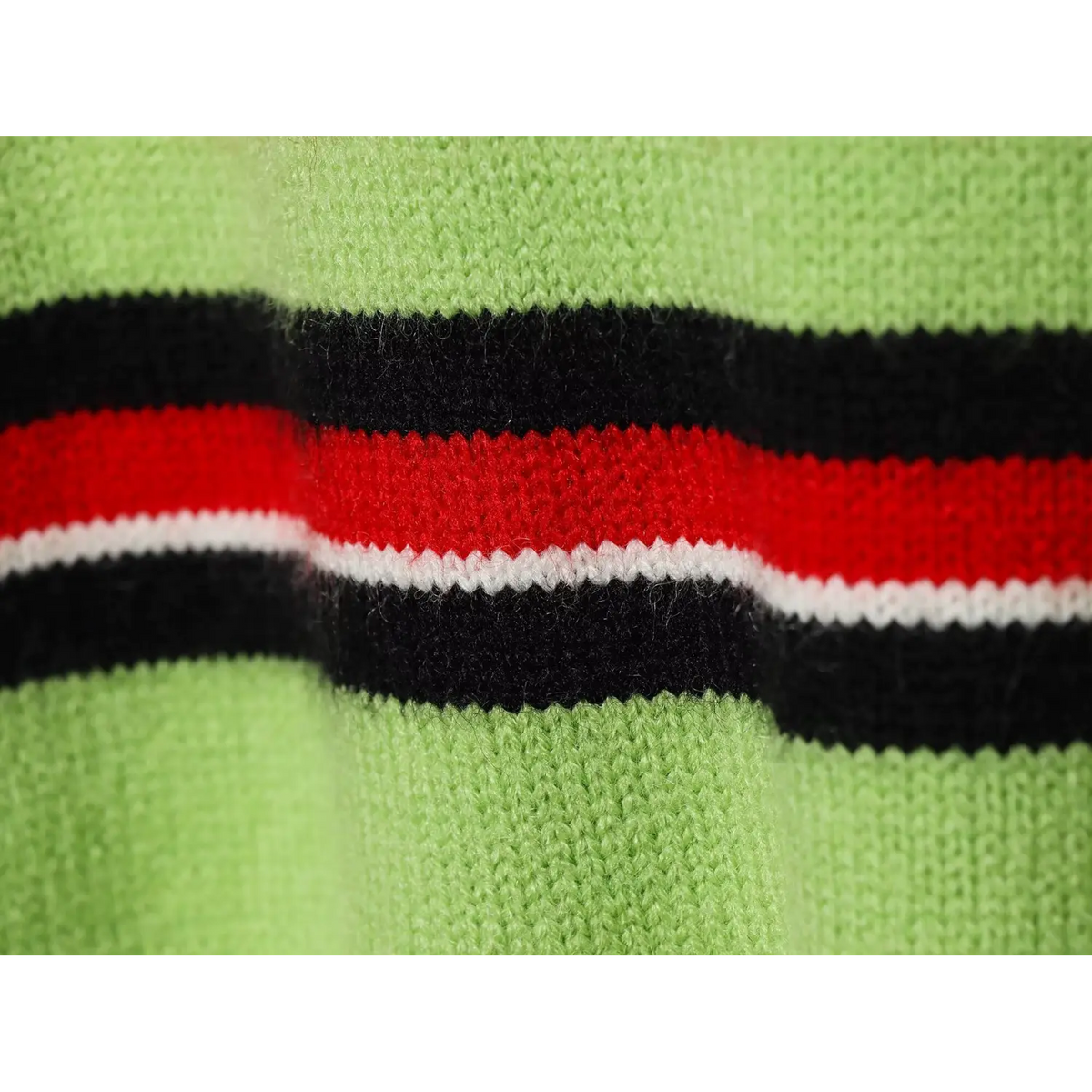 Close-up of black, red and white horizontal stripe trim on green knit fabric
