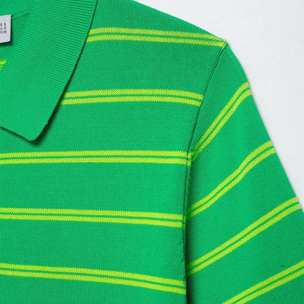 Close-up of the shoulder and collar on the green and yellow striped knit polo shirt, showing the ribbed polo collar and seam details