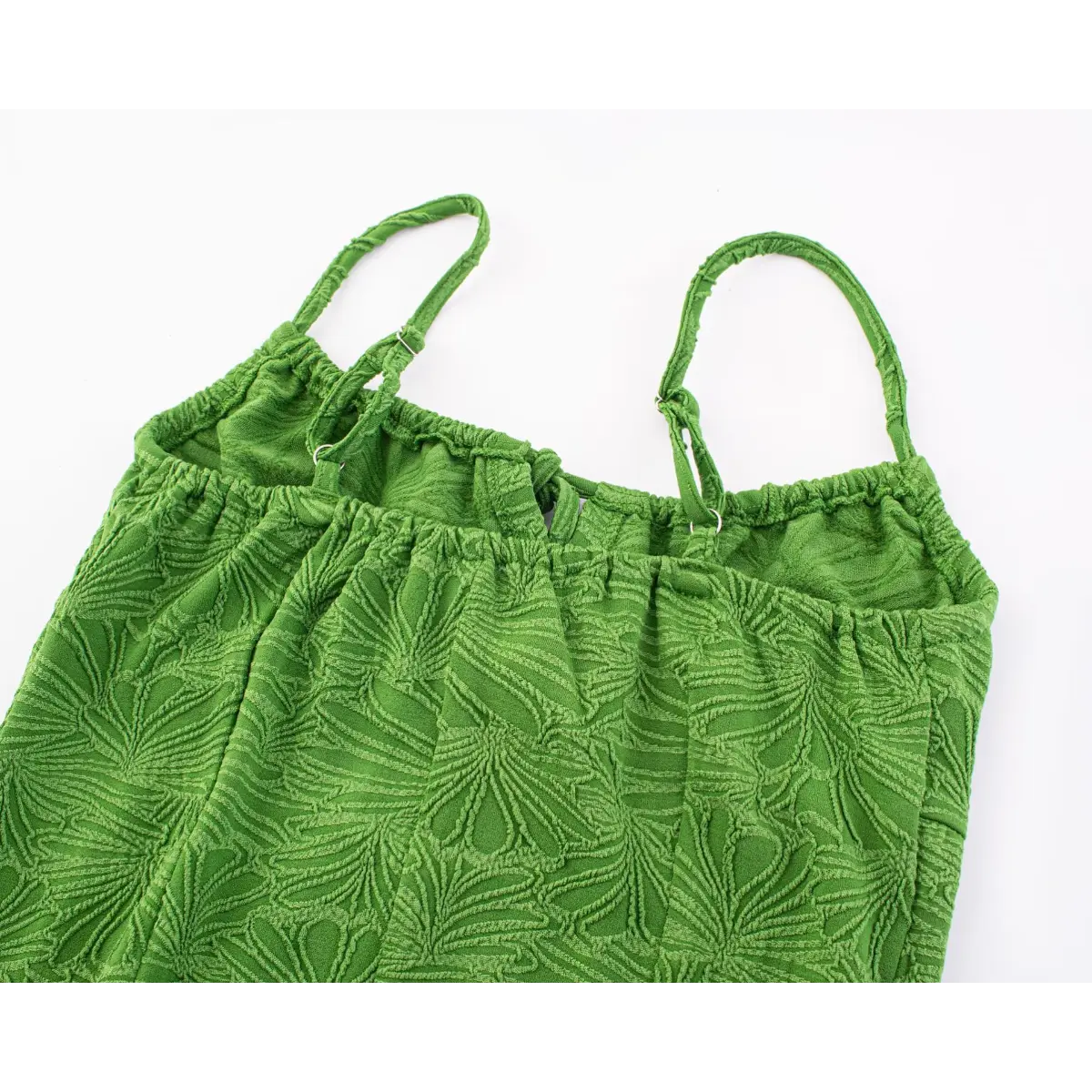 Close-up view of the back bust area of a green textured mini dress with spaghetti straps, showing the adjustable sliders and elasticated top edge.