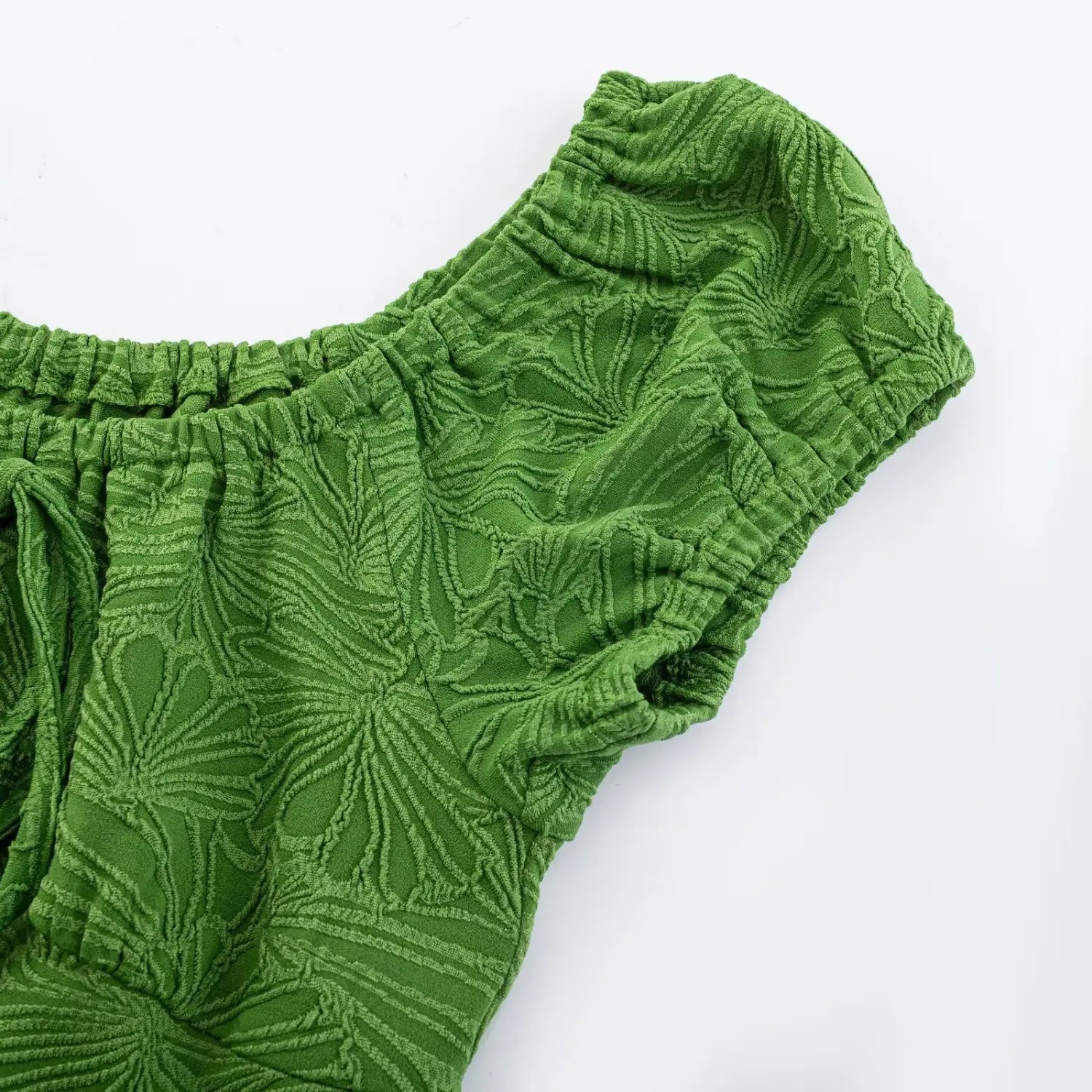 Angled flat partial shot of green embossed ginkgo knit dress, stretch gathered square neck and ruched bubble short sleeve fabric detail