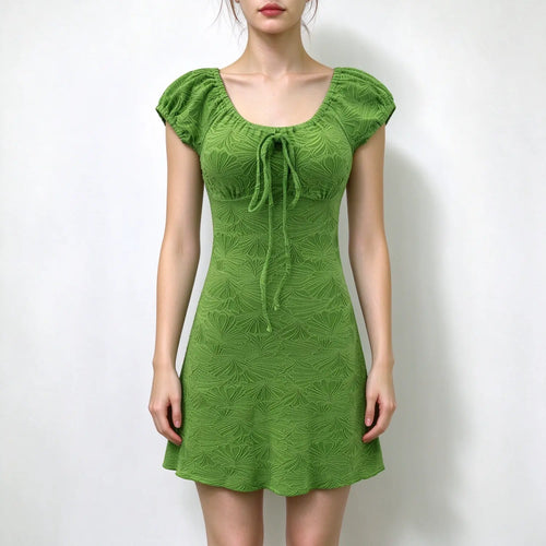 Model wearing green textured puff sleeve mini dress with square neck and front tie detail, plain white background
