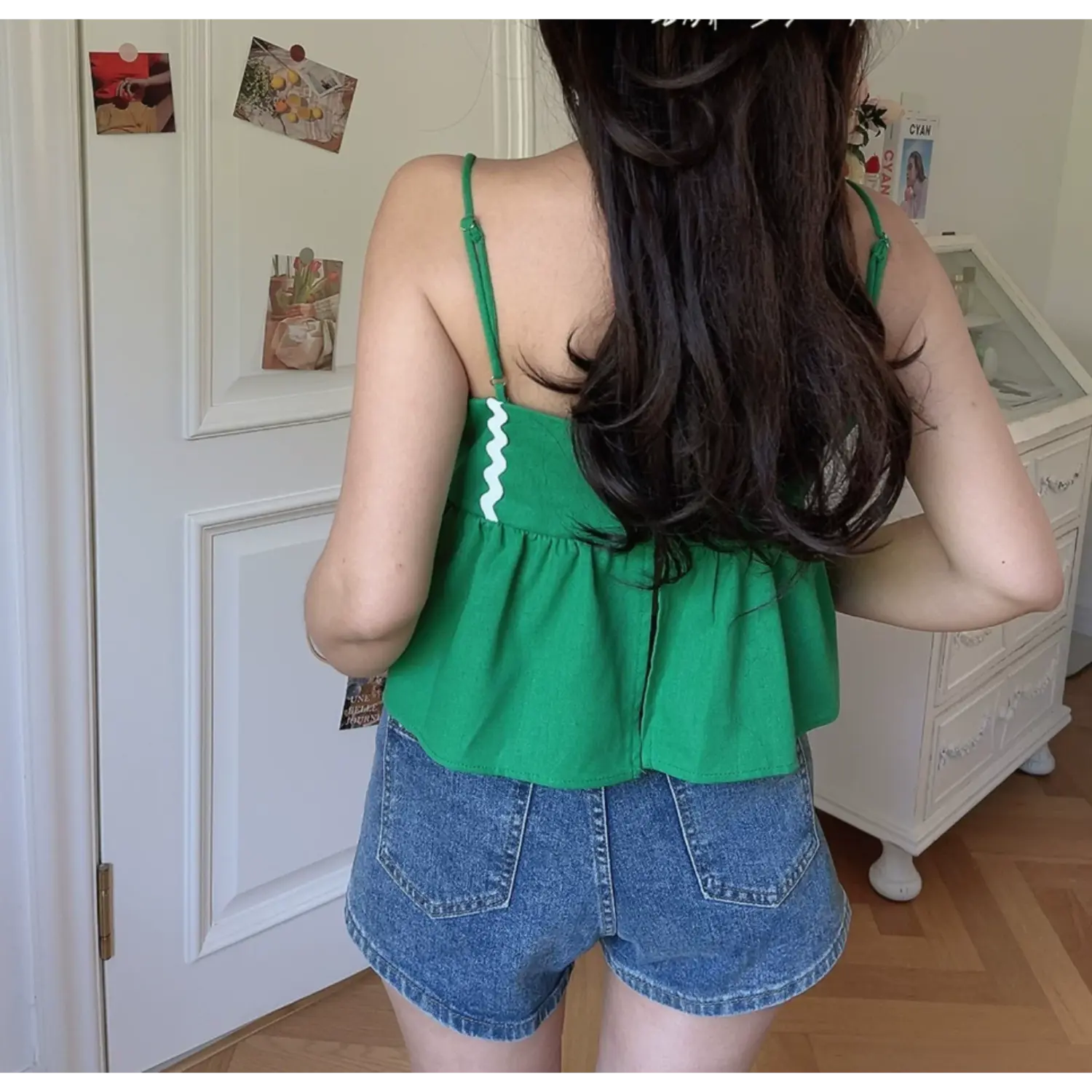 Lifestyle back shot of model wearing the green wavy-edge peplum camisole top