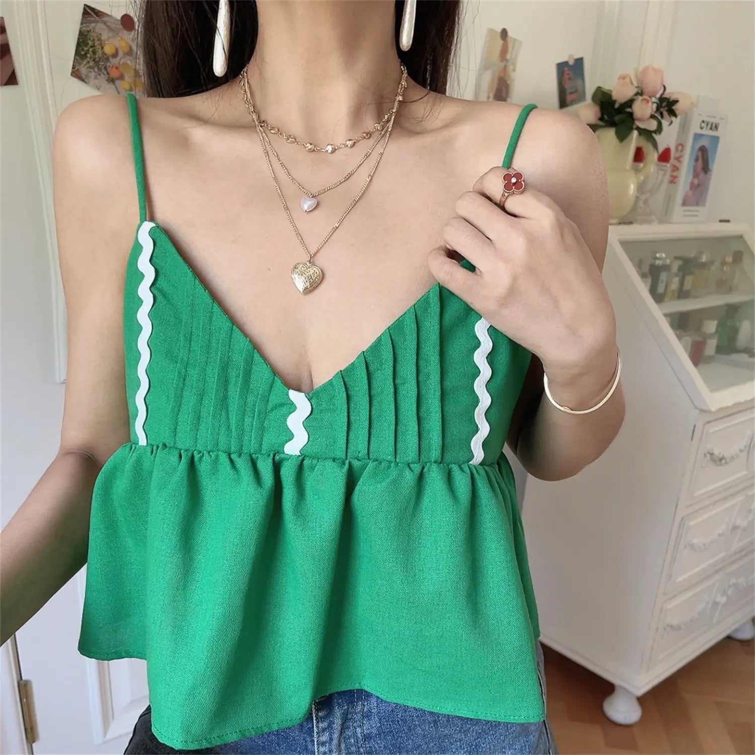Lifestyle shot of model wearing the green wavy-edge peplum camisole top with jeans