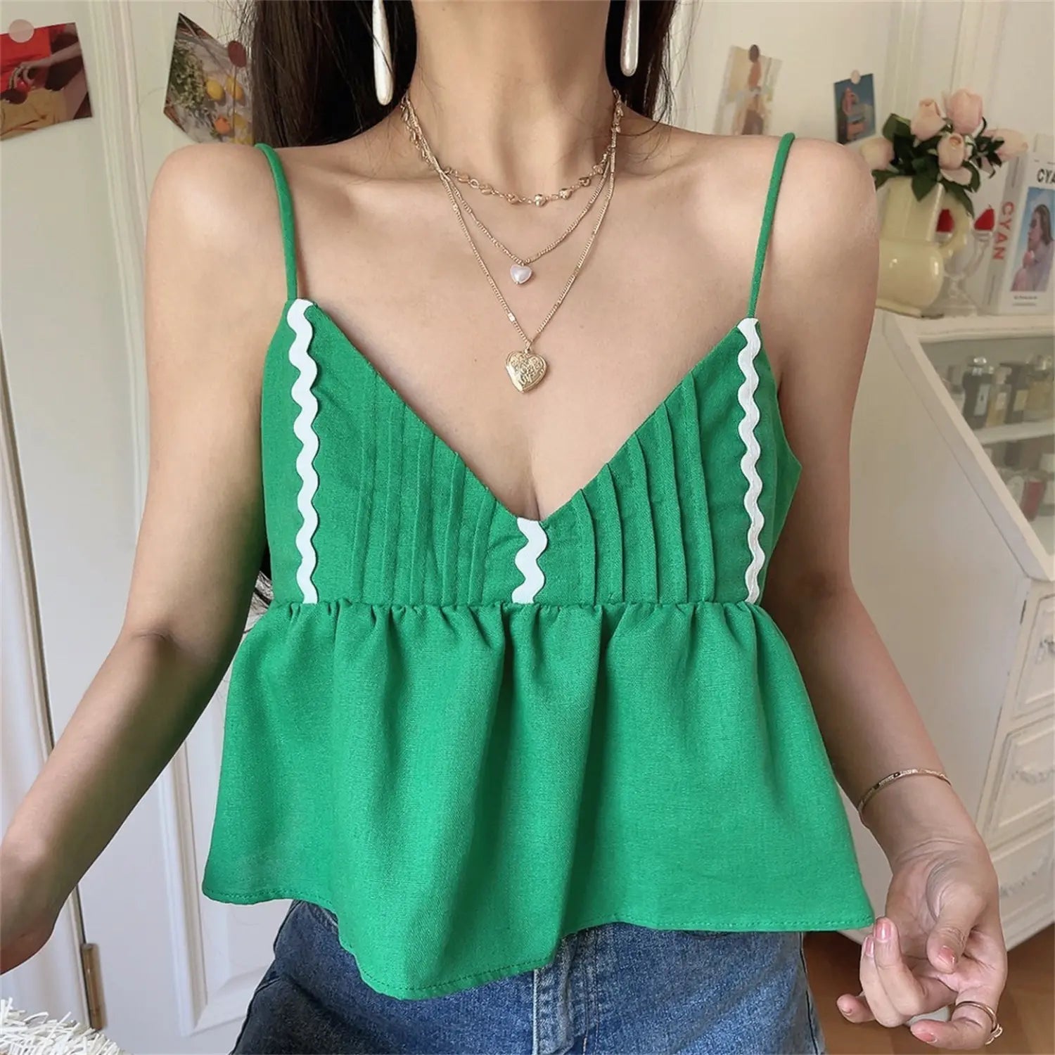 Close-up lifestyle shot of model wearing the green wavy-edge peplum camisole top