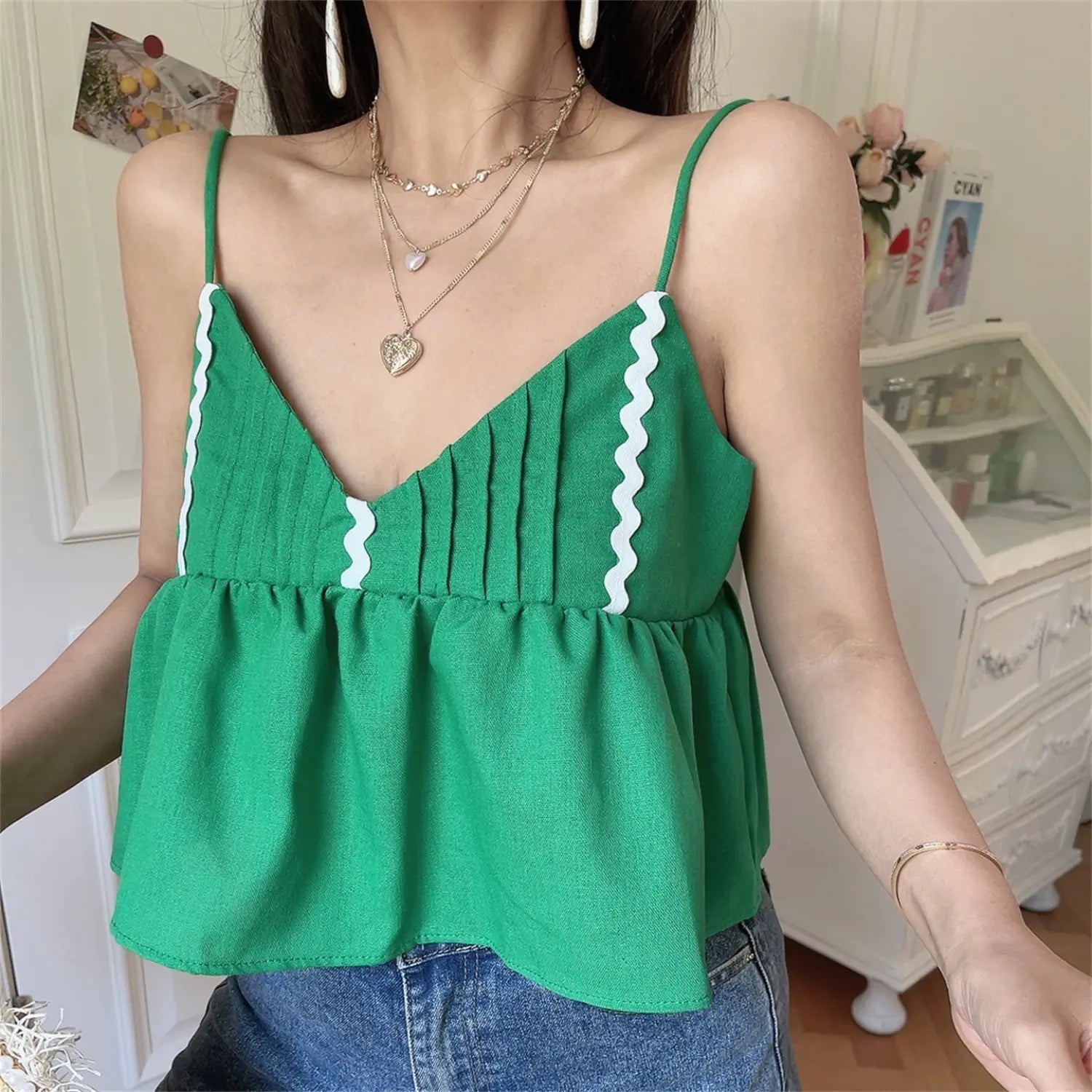 Front view lifestyle shot of the green wavy-edge peplum camisole top