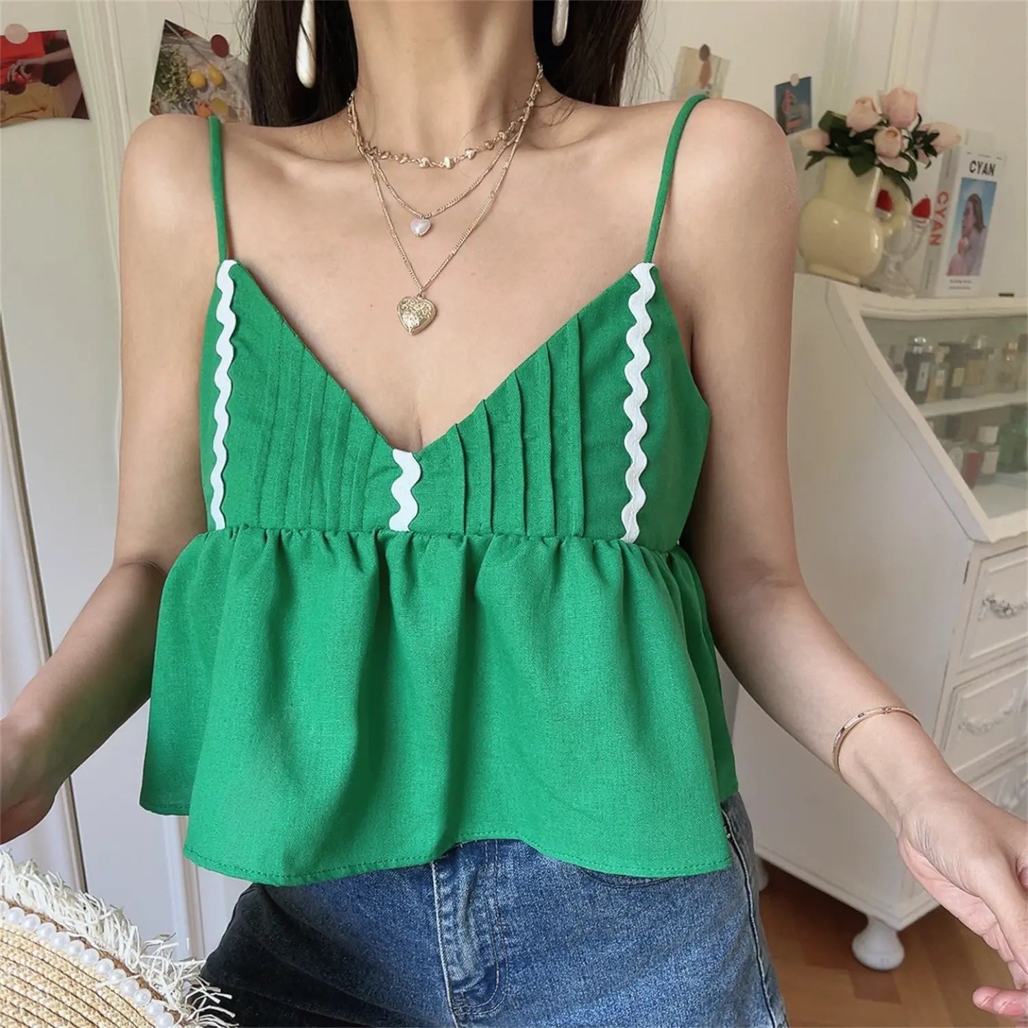 Close-up shot of model wearing the green wavy-edge peplum camisole top