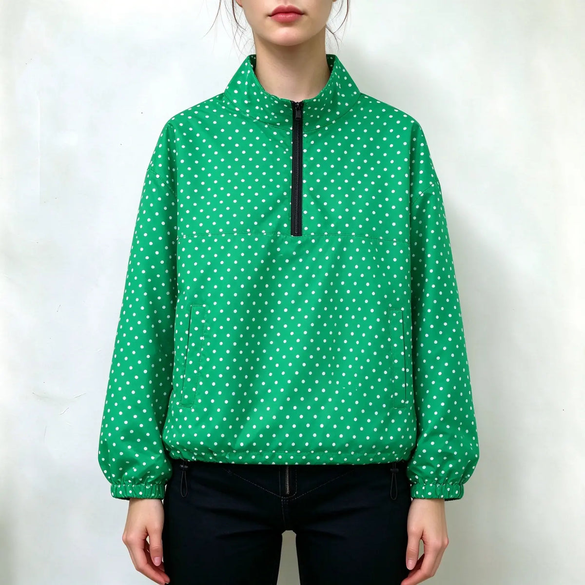 Model wearing green wind jacket with white polka dots, stand collar, half black zipper, side pockets, elastic cuffs and hem, paired with black pants, plain white background
