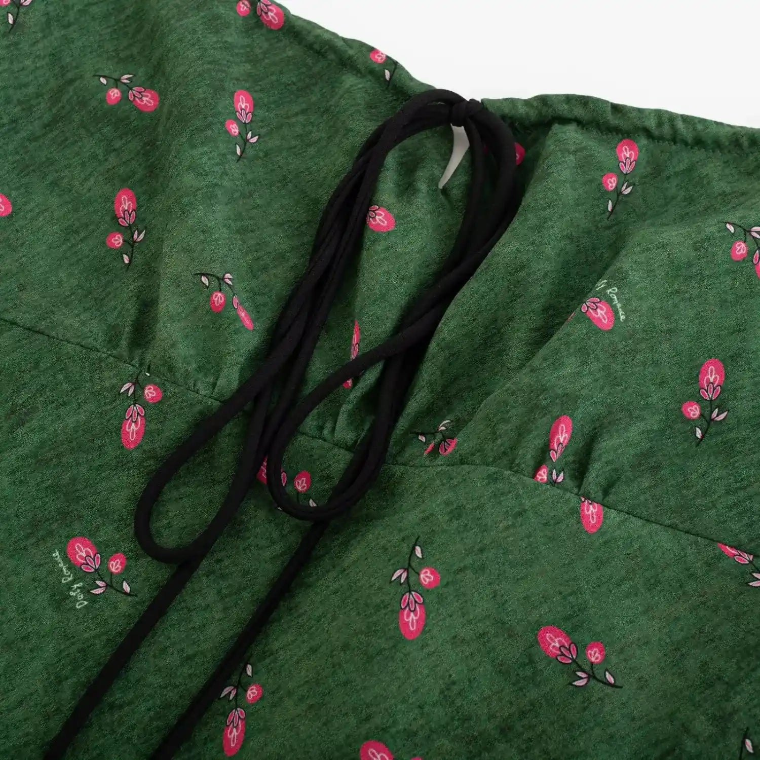 Close‑up of front neck tie detail on green fruit print cami dress