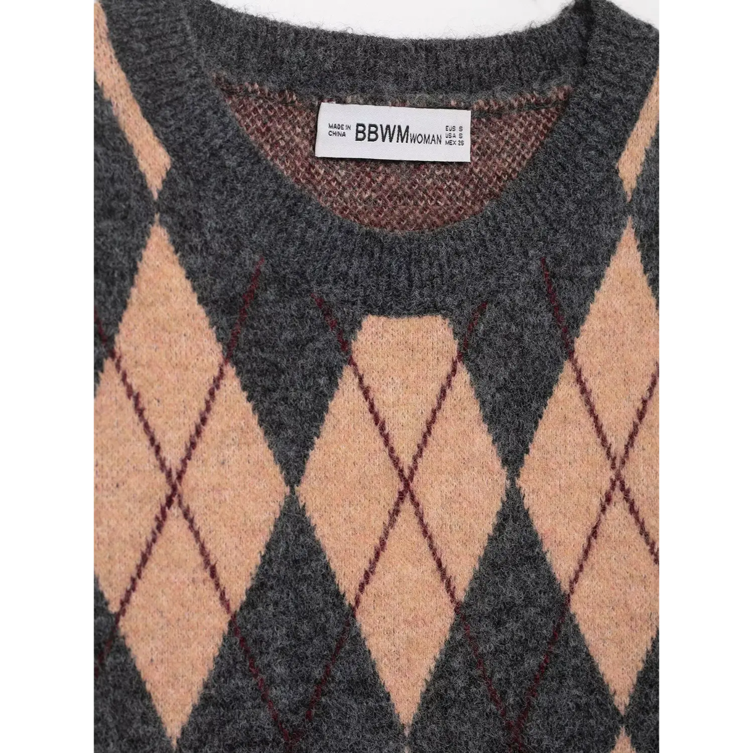 Close-up of the crew neckline, inner brand label, and argyle pattern on grey-beige knit vest