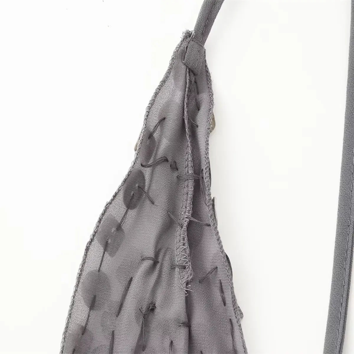 Close-up of the halter strap on the grey chiffon dress, showing the inner construction and shell button stitching