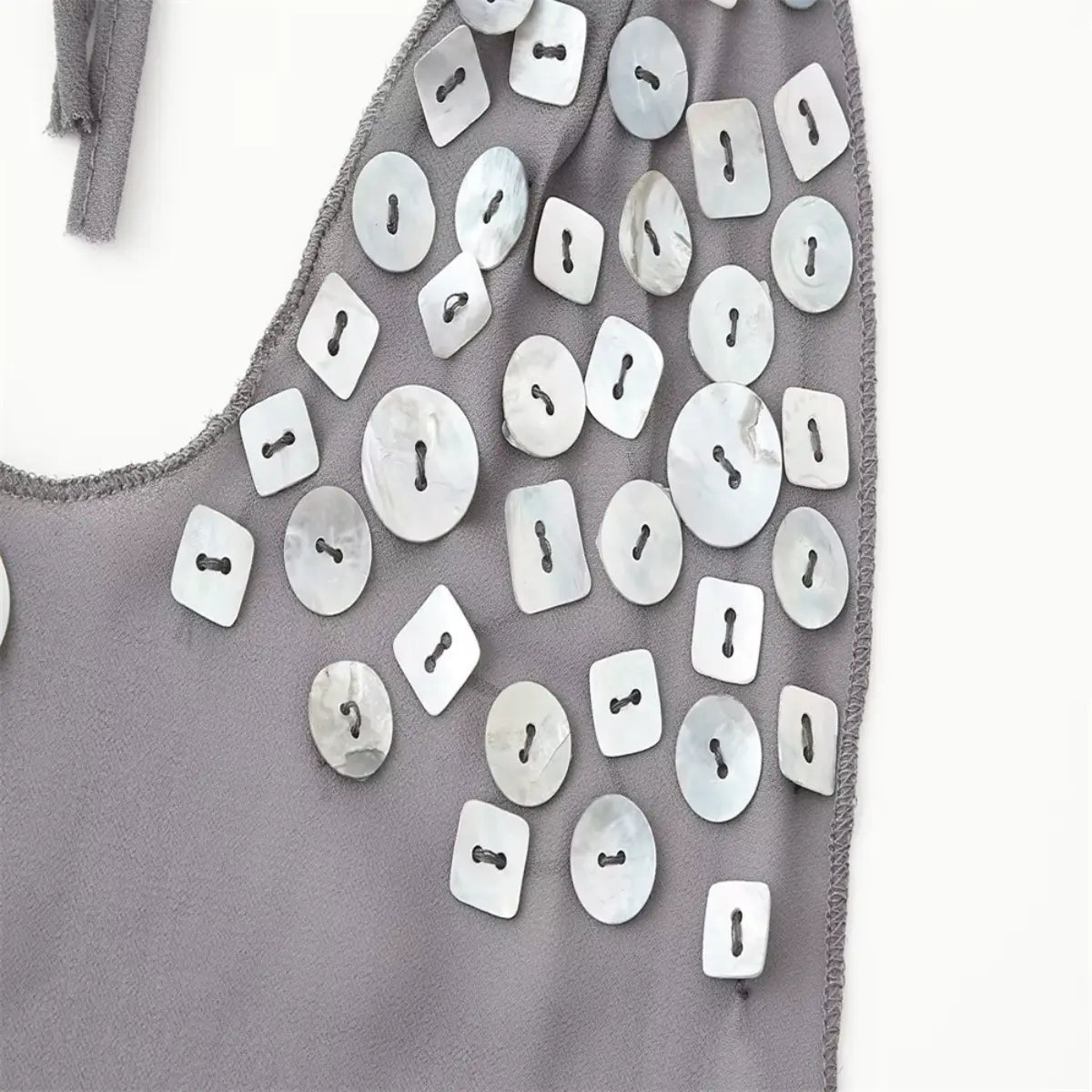 Close-up of the dress neckline, showing the scattered shell buttons and raw-edge trim