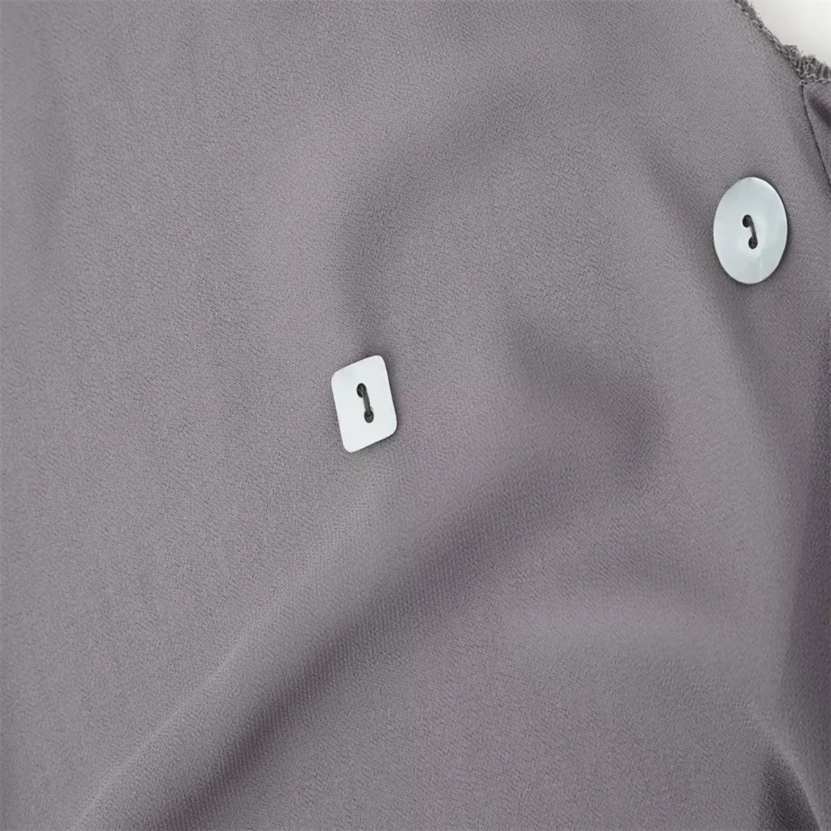 Close-up of the shell buttons on the grey chiffon dress, featuring both round and square shapes