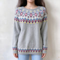 Female model wears light grey fairisle pullover, multi-colored diamond jacquard on yoke and sleeve cuffs, crew neck loose fit knit sweater, front torso shot