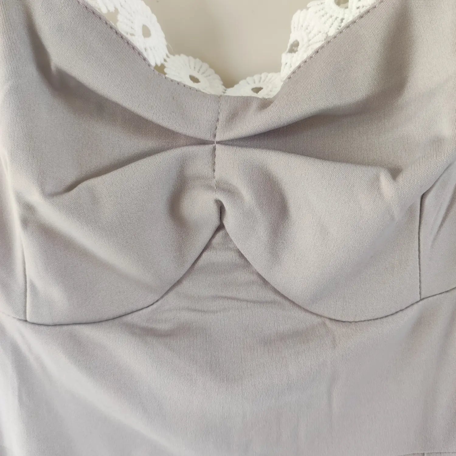 Close‑up front bust twist fabric detail of grey fitted sleeveless midi dress