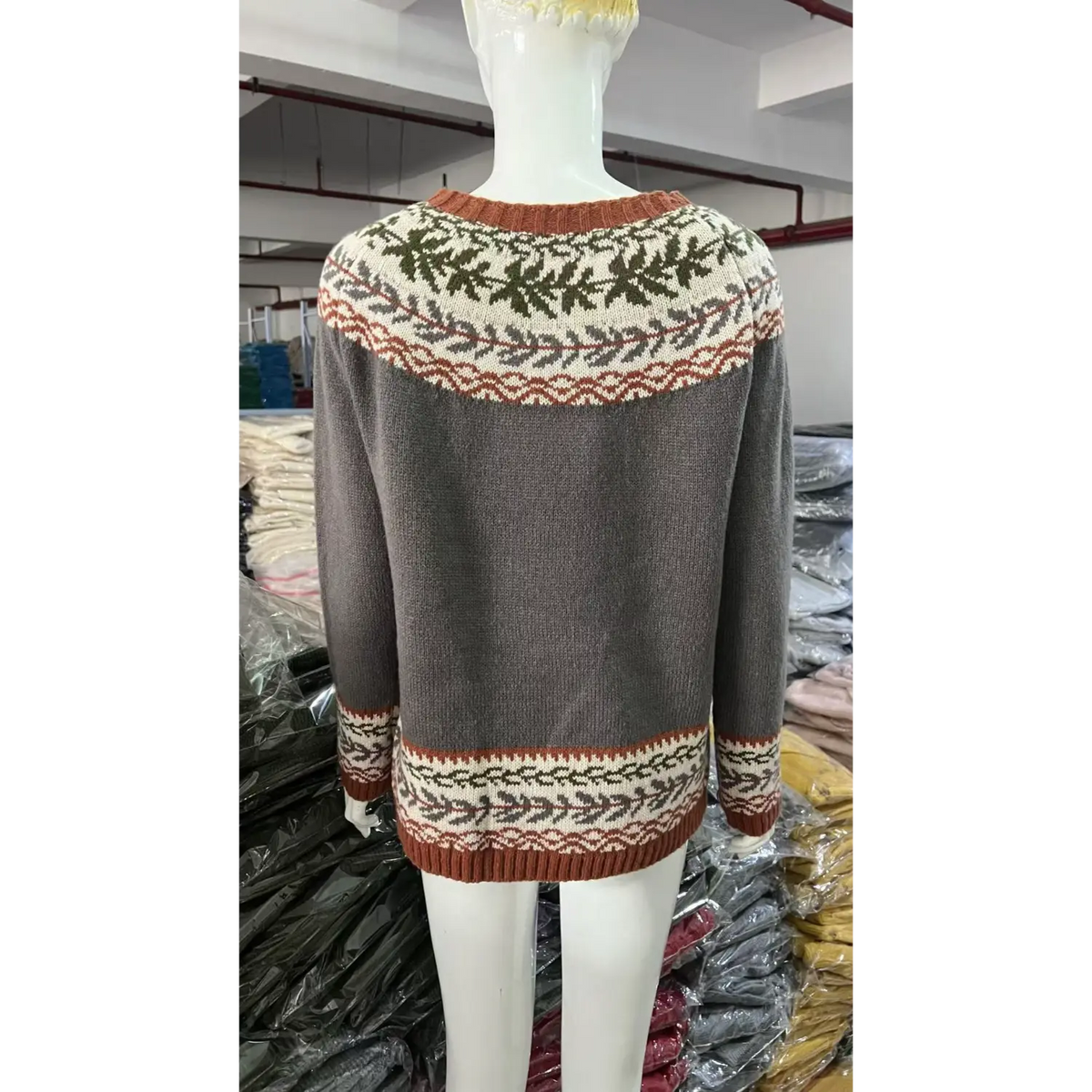 Back view of white mannequin showing grey fairisle sweater, vintage leaf jacquard knit pattern, factory background