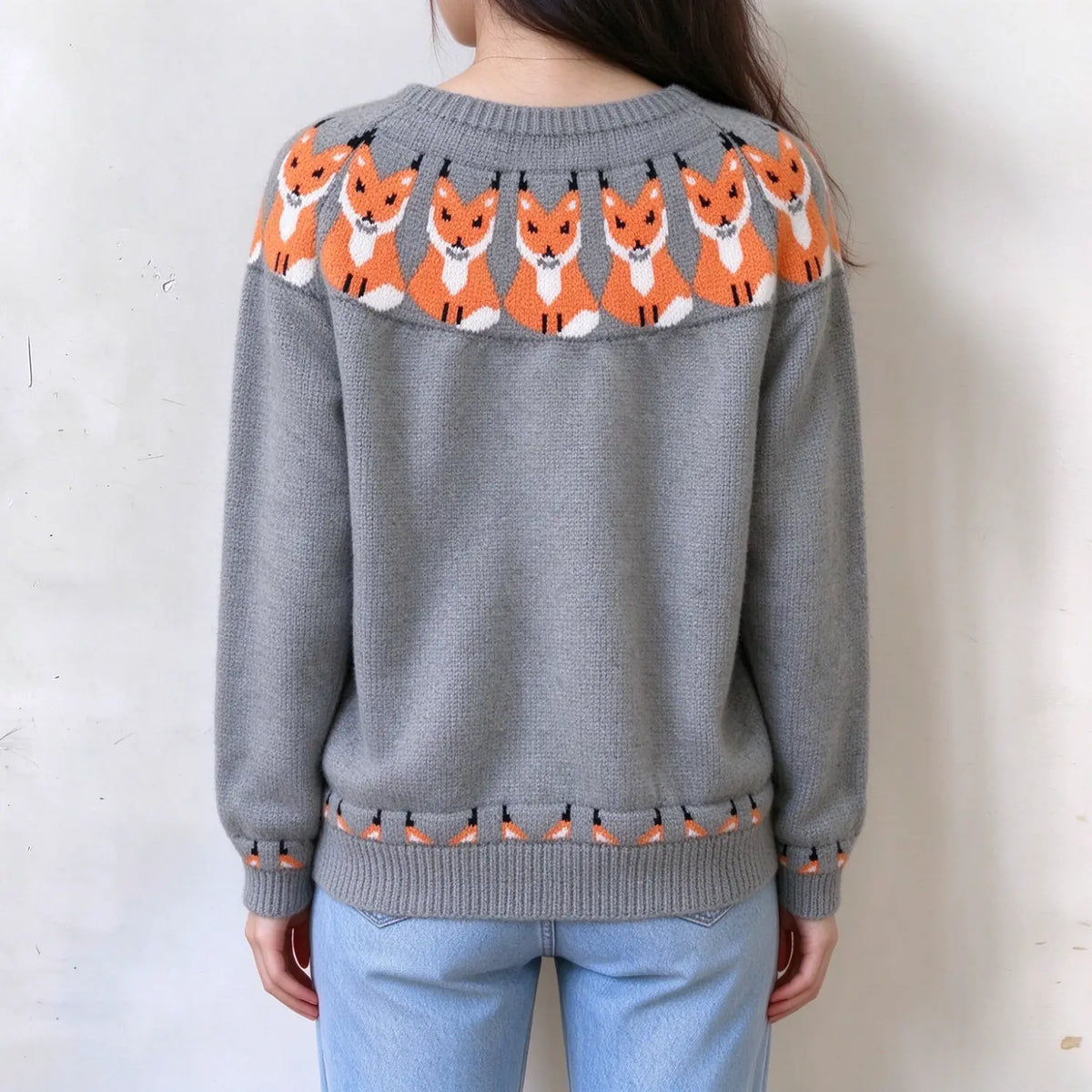 Model back view wearing grey knit pullover sweater, cute orange fox jacquard pattern around neckline and hem, long sleeve crew neck sweater, plain white wall background