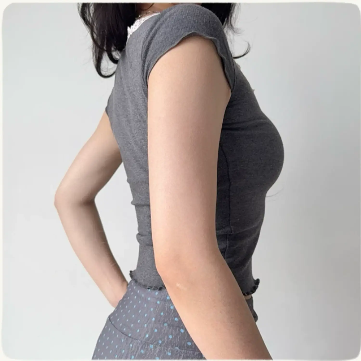 Lifestyle back shot of a woman wearing a grey ribbed tee with lace trim at the neckline and hem