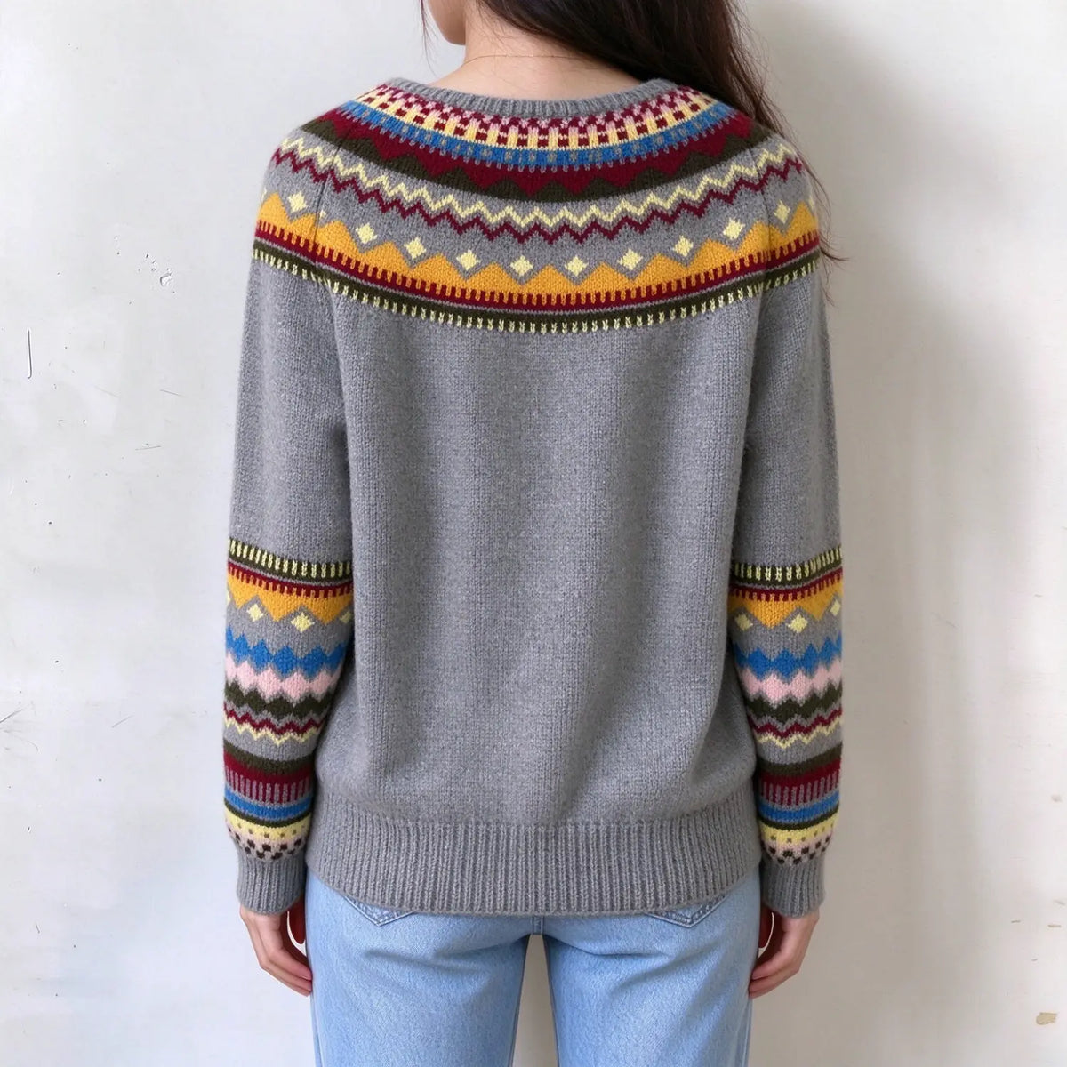 Female model back view, grey fairisle knit sweater, multi color zigzag and diamond jacquard pattern on yoke and sleeves, ribbed cuffs