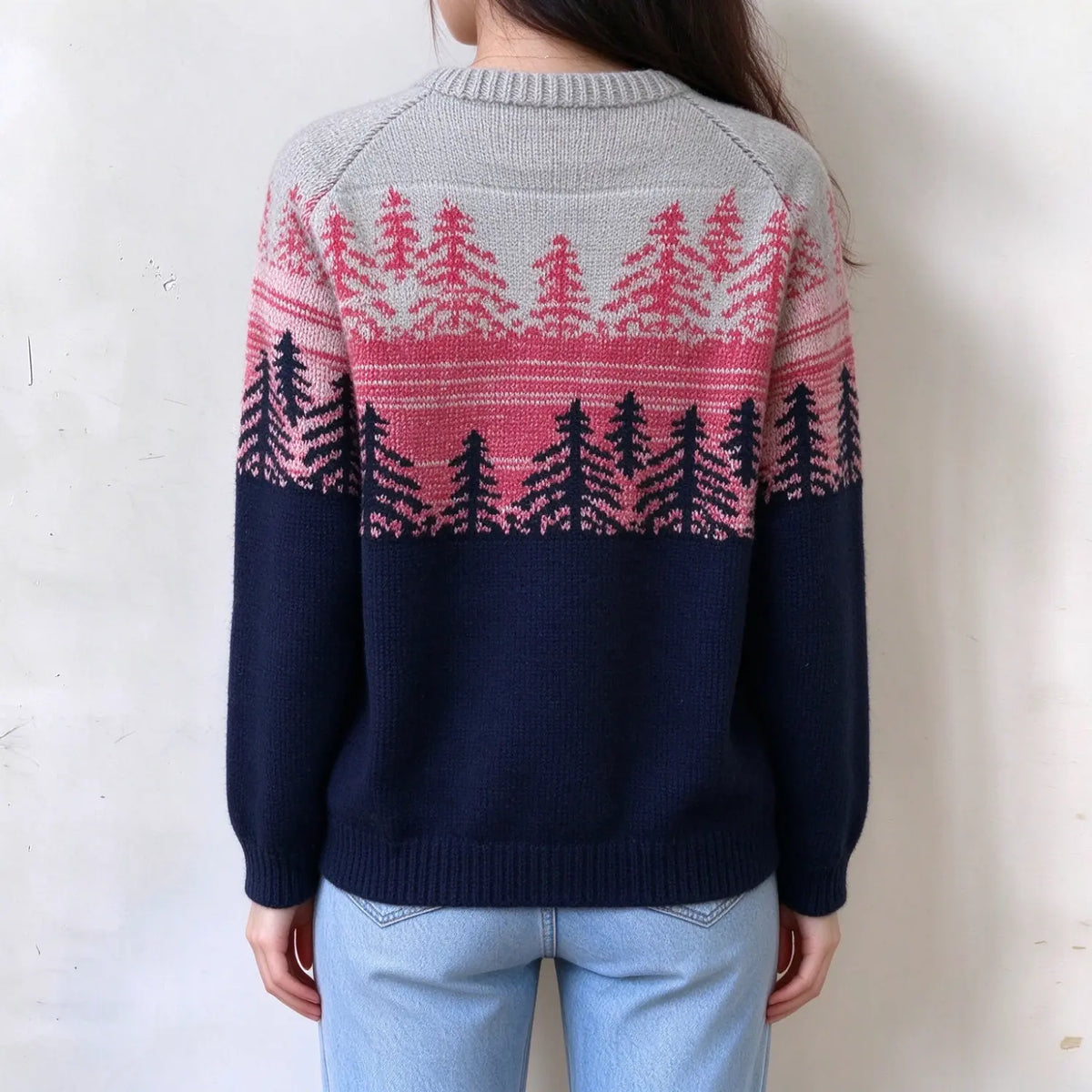 Female model back view, two tone fairisle sweater, light grey upper with pink pine tree print, navy blue lower body, ribbed hem