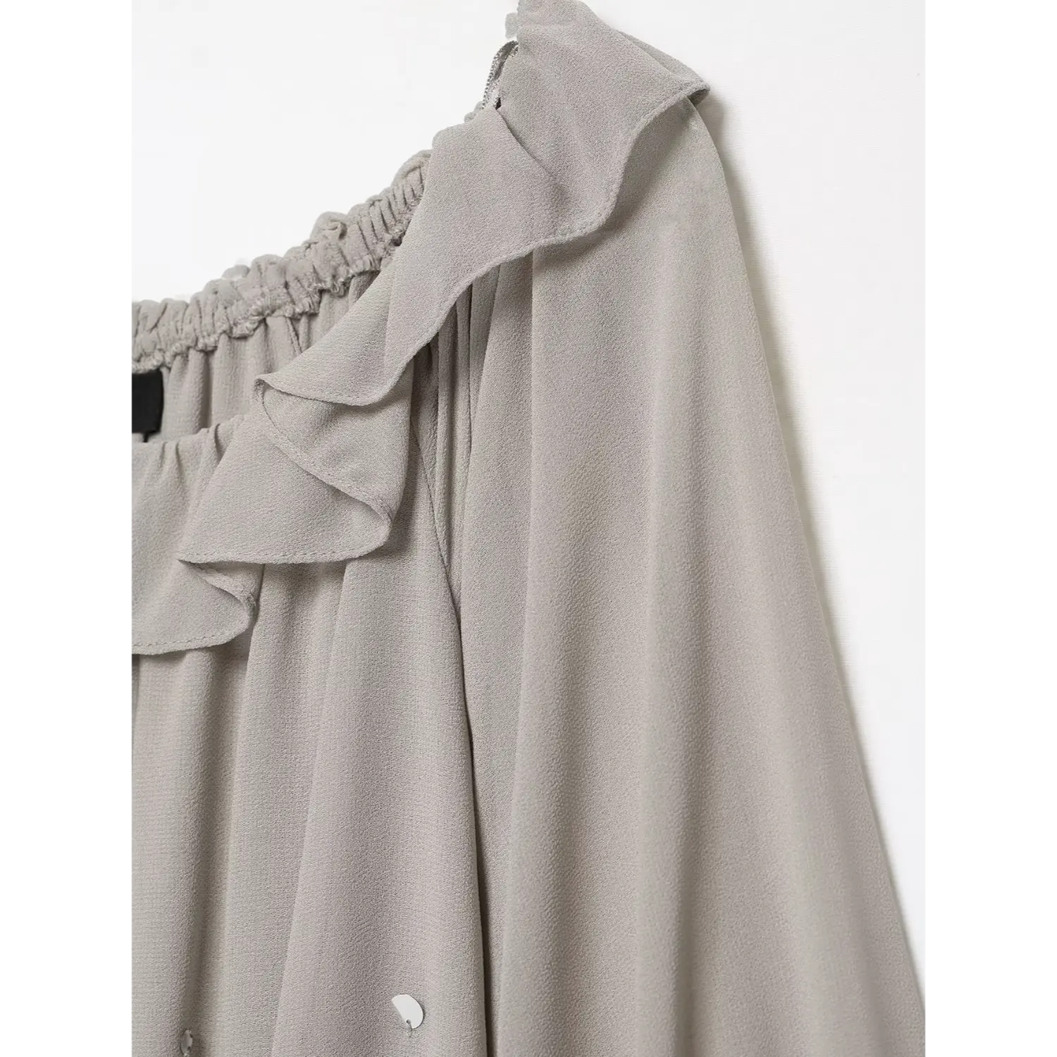 Side close‑up of off‑shoulder ruffle trim and sleeve seam, flowy grey sheer chiffon construction detail