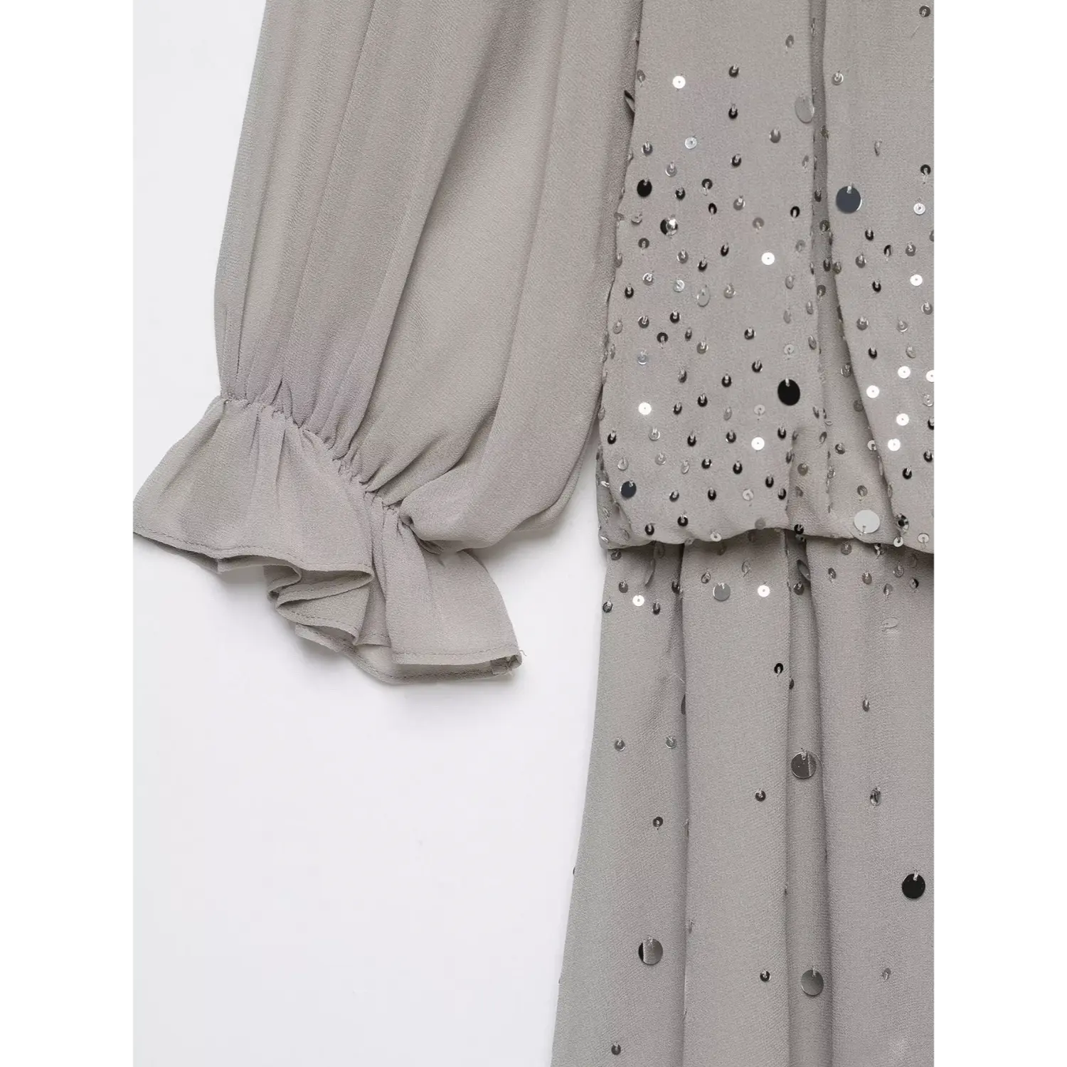 Close‑up of ruffled balloon sleeve cuff, scattered silver sequins on grey flowy chiffon material