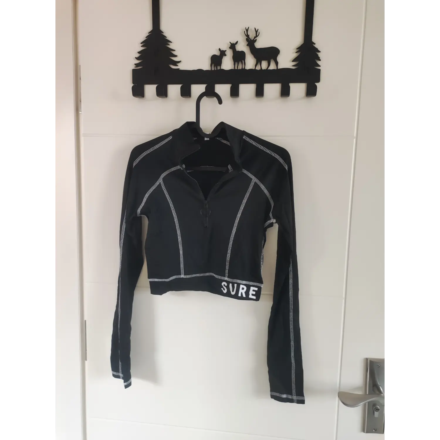 Hanging front shot black stand collar half zip long sleeve crop top with white SURE print on hem