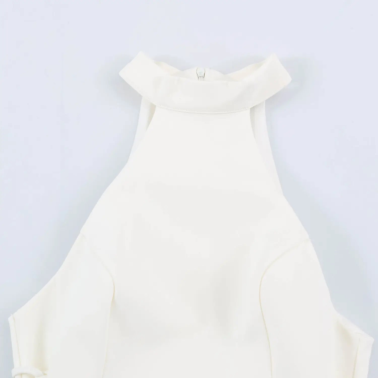 Close-up of halter neck collar and back zipper on white sleeveless mini dress