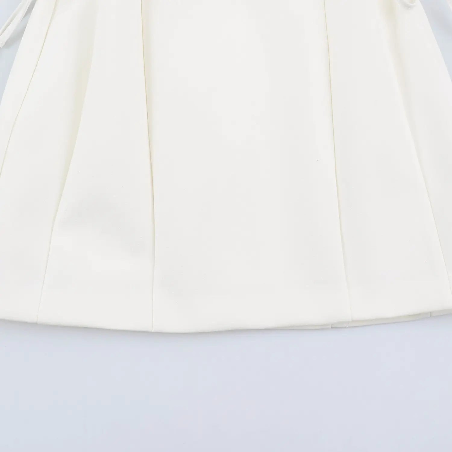 Front skirt panel stitching detail of white sleeveless halter mini dress