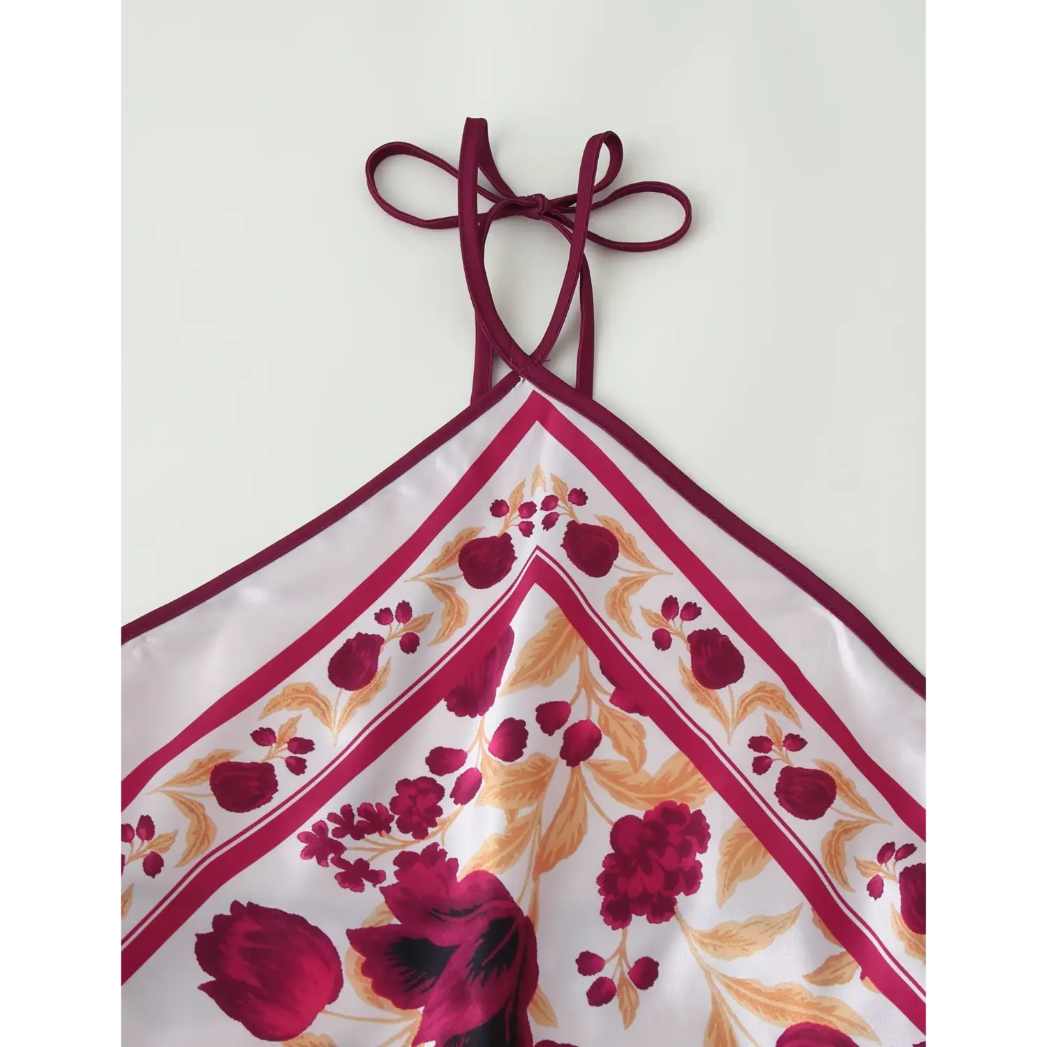Close‑up of halter tie strap and upper bodice, burgundy tulip floral bandana print, satin fabric trim detail