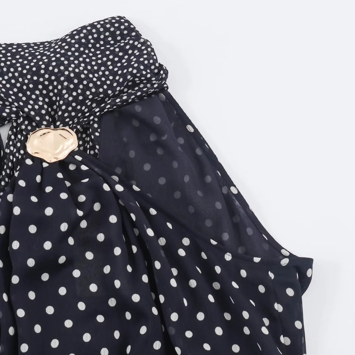 Close‑up of sleeveless shoulder and neck fabric for navy polka dot halter maxi dress